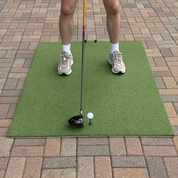 Person hitting a golf ball on a turf hitting mat