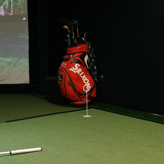 a golf bag in a golf simulator sitting on top of a BirdieBall tour turf putting mat