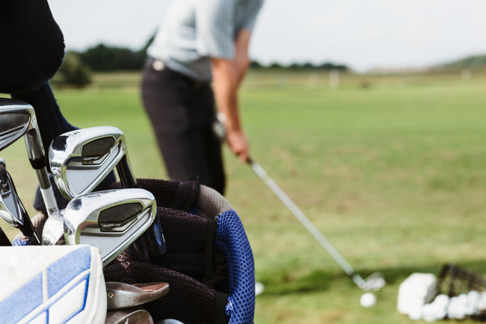 golfer practicing at driving range with golf bag in the foreground