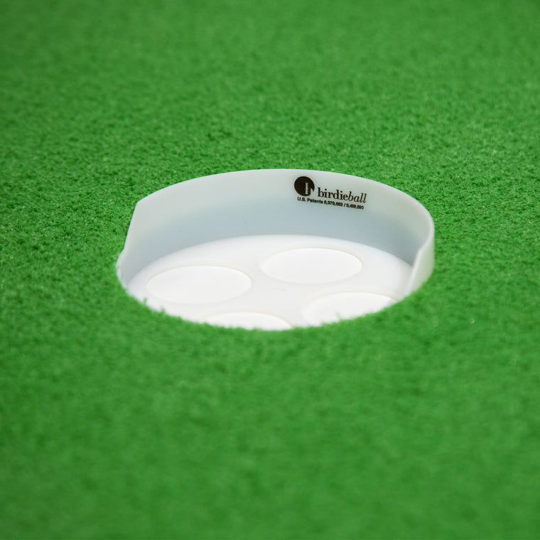 Close-up of the BirdieBall High Back Putting Green Cup (1/2" deep) set in artificial green turf, featuring the "birdieball" logo on the rim—an essential component of the BirdieBall putting system.